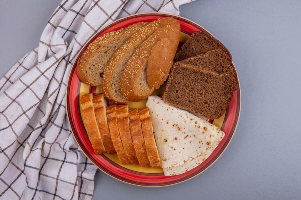 top-view-breads-as-sliced-seeded-brown-cob-rye-baguette-flatbread-plate-plaid-cloth-gray-background_141793-27730.jpg
